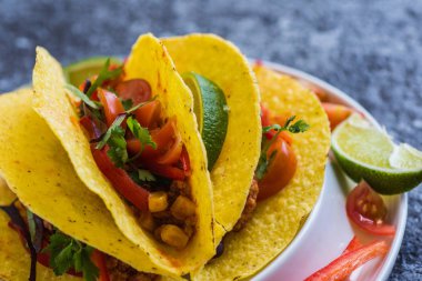 Kabuklarında gri arka plan üzerinde renkli Meksika Tacos