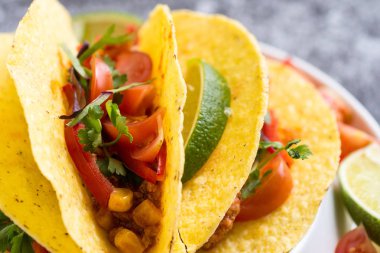 Kabuklarında gri arka plan üzerinde renkli Meksika Tacos