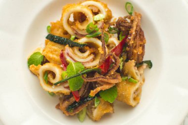 Fried Squids kalamar, biber ve nane yaprakları üzerinde beyaz Pla