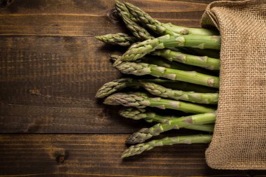 Juta çanta ahşap arka plan üzerinde taze kuşkonmaz