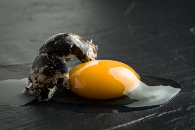 Karanlık taş zemin üzerine çiğ kırık yumurta sarısı. Taze organik gıda