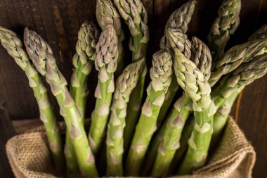 Juta çanta ahşap arka plan üzerinde taze kuşkonmaz