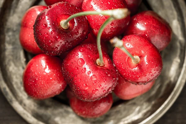 Cerezas rojas frescas húmedas en placa rústica — Foto de Stock