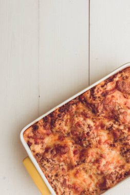 Lazanya Bolognese sığır eti, domates sosu ve rustik beyaz ahşap masa üzerinde yeşil fesleğen ile