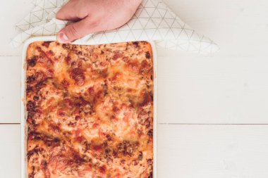 İtalyan lazanya Bolognese sığır eti, domates sosu ve rustik beyaz ahşap zemin üzerine Yeşil fesleğen ile