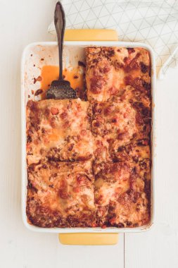 İtalyan lazanya Bolognese sığır eti, domates sosu ve rustik beyaz ahşap zemin üzerine Yeşil fesleğen ile