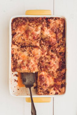 İtalyan lazanya Bolognese sığır eti, domates sosu ve rustik beyaz ahşap zemin üzerine Yeşil fesleğen ile