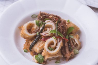 Taze kızarmış Squids kalamar, kırmızı sıcak biber biber ve yeşil nane yaprakları beyaz plaka üzerinde