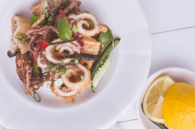 Yunan Fried Squids kalamar ile kırmızı biber biber ve taze nane yaprakları beyaz plaka üzerinde