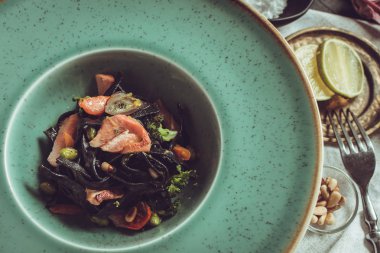 Mürekkep balığı somon ve sebze yeşil plaka üzerinde siyah spagetti mürekkep