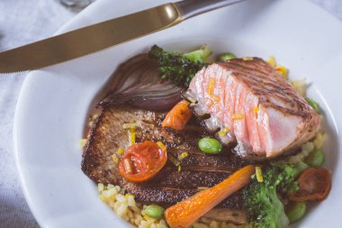 Rustik beyaz tabakta sebze ile somon fileto