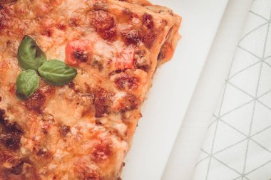 Kıyma, domates sosu ve beyaz plaka üzerinde taze fesleğen ile ev yapımı lazanya