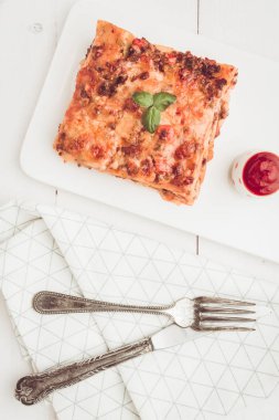 Kıyma, domates sosu ve beyaz plaka üzerinde taze fesleğen ile ev yapımı lazanya
