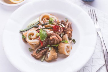 Taze kızarmış Squids kalamar, kırmızı sıcak biber biber ve yeşil nane yaprakları beyaz plaka üzerinde