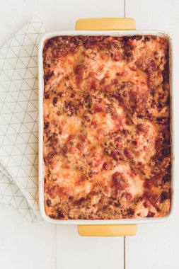 İtalyan lazanya Bolognese sığır eti, domates sosu ve rustik beyaz ahşap zemin üzerine Yeşil fesleğen ile