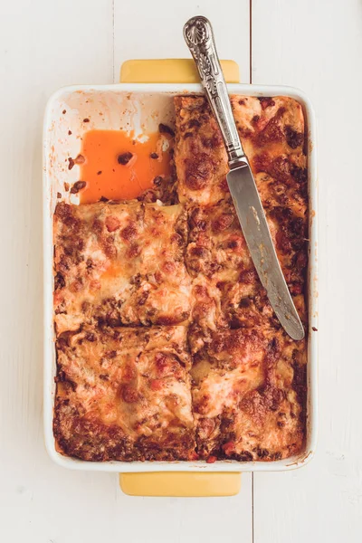 İtalyan lazanya Bolognese sığır eti, domates sosu ve rustik beyaz ahşap zemin üzerine Yeşil fesleğen ile