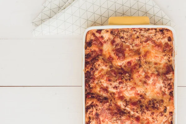 İtalyan lazanya Bolognese sığır eti, domates sosu ve rustik beyaz ahşap zemin üzerine Yeşil fesleğen ile