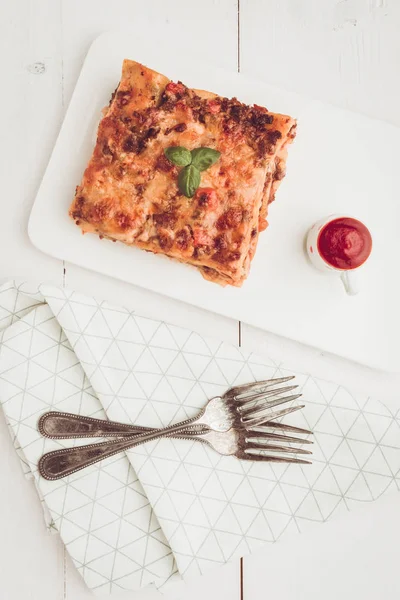 Kıyma, domates sosu ve beyaz plaka üzerinde taze fesleğen ile ev yapımı lazanya
