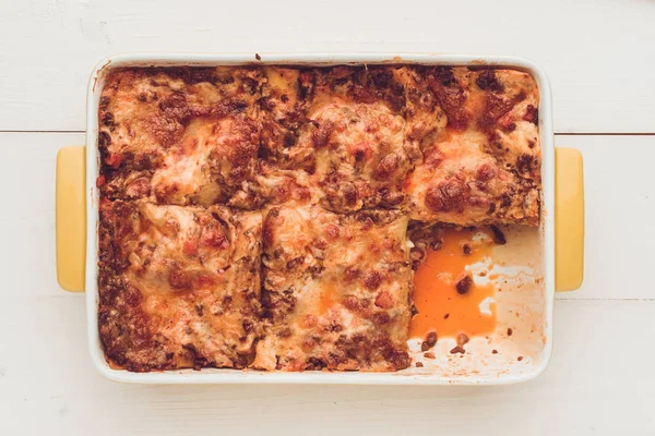 İtalyan lazanya Bolognese sığır eti, domates sosu ve rustik beyaz ahşap zemin üzerine Yeşil fesleğen ile