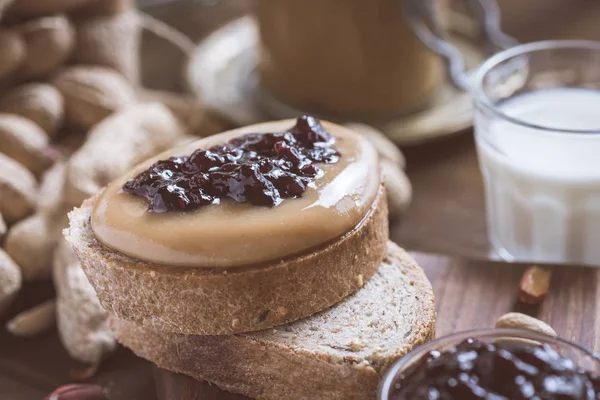 Taze fıstık ezmesi ve jöle sandviç eski rustik ahşap kesme tahtası üzerinde