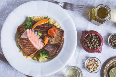 Rustik beyaz tabakta sebze ile somon fileto