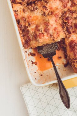 İtalyan lazanya Bolognese sığır eti, domates sosu ve rustik beyaz ahşap zemin üzerine Yeşil fesleğen ile