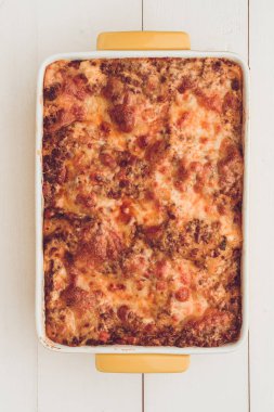 Lazanya Bolognese sığır eti, domates sosu ve rustik beyaz ahşap masa üzerinde yeşil fesleğen ile