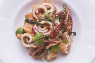 Taze kızarmış Squids kalamar, kırmızı sıcak biber biber ve yeşil nane yaprakları beyaz plaka üzerinde