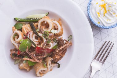 Yunan Fried Squids kalamar ile kırmızı biber biber ve taze nane yaprakları beyaz plaka üzerinde