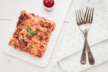 Kıyma, domates sosu ve beyaz plaka üzerinde taze fesleğen ile ev yapımı lazanya