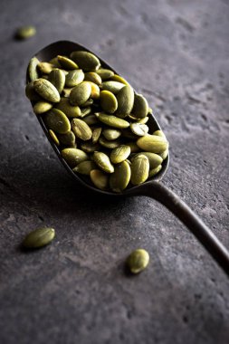 Rustik koyu arka plan üzerinde kaşık çiğ kabak çekirdeği