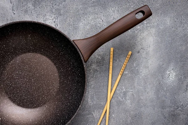 Wok Pan vazio com pauzinhos de madeira no fundo escuro. Topo Vie — Fotografia de Stock