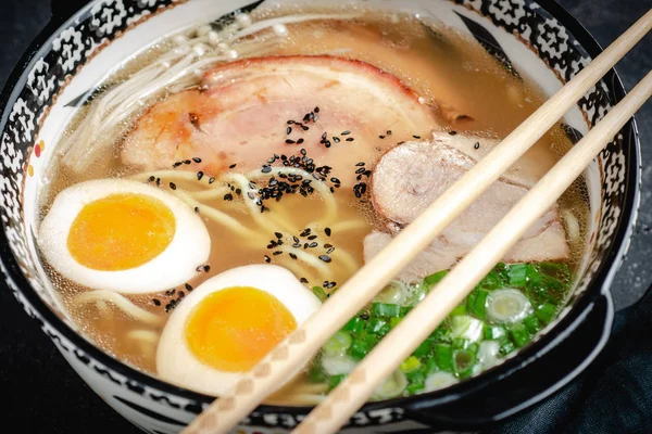 Zuppa di ramen giapponese con tagliatelle di Udon, maiale, uova e scalogno su sfondo scuro di pietra — Foto Stock