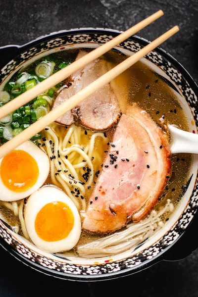 Zuppa di ramen giapponese con tagliatelle di Udon, maiale, uova e scalogno su sfondo scuro di pietra — Foto Stock