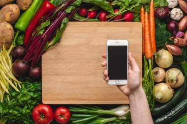 Taze Organik Sebzeler Arka Plan üzerinde Smartphone ile El. Vegan Yemek Tarifleri.
