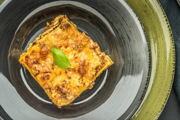 Итальянская лазанья с мясом и зеленым базиликом на темной тарелке — стоковое фото