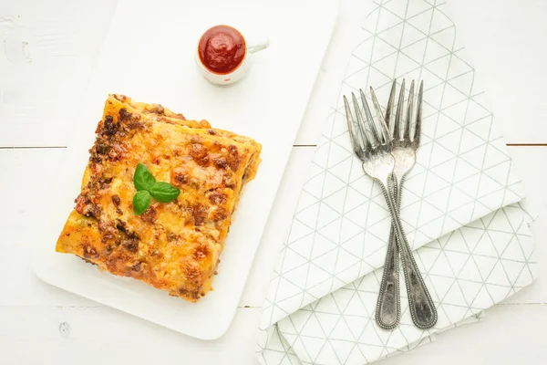 Свежая итальянская лазанья с мясом, томатным соусом и свежим базиликом на белом фоне — стоковое фото