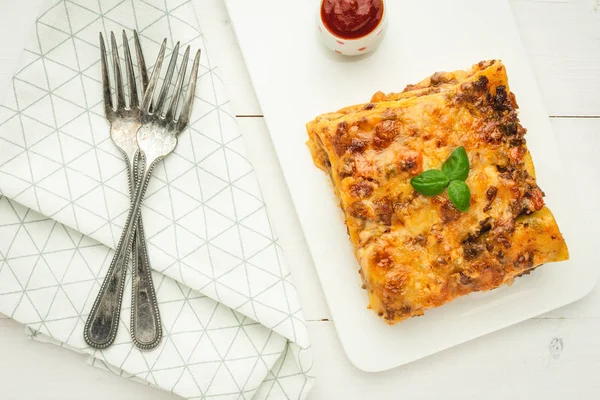 Свежая итальянская лазанья с мясом, томатным соусом и свежим базиликом на белом фоне — стоковое фото