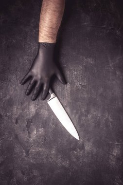 Siyah lateks eldiven ve koyu arka planda bıçak ile erkek eller