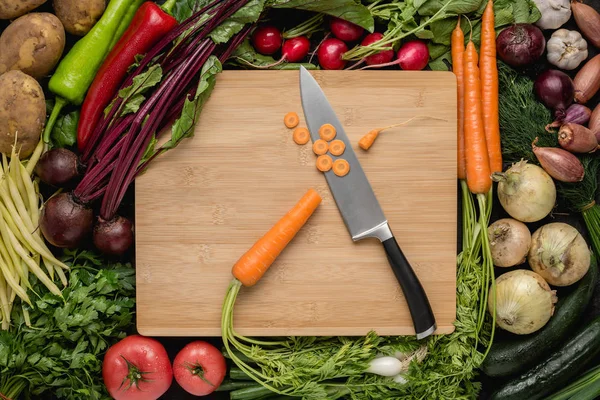 Kitchen Chef Knife with Fresh Vegetables on Wood Cutting Board. Vegetarian Raw Food. Healthy Eating Concept.