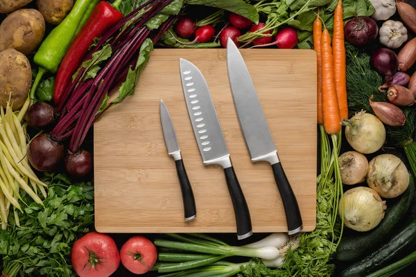 Juego de cuchillos de cocina con verduras frescas en tabla de cortar de madera. Comida Cruda Vegetariana. Concepto de alimentación saludable . —  Fotos de Stock