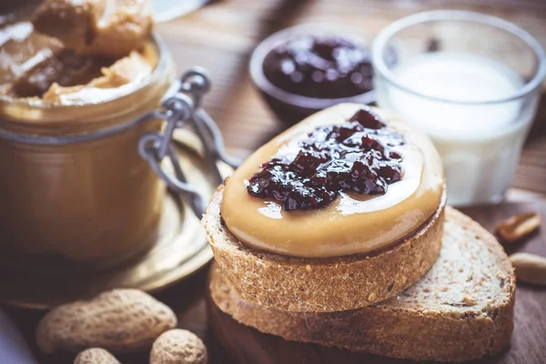 Mantequilla de cacahuete y jalea en la tabla de cortar madera rústica. Desayuno saludable casero . — Foto de Stock