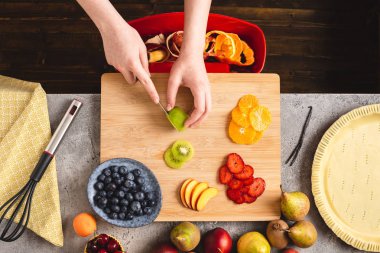 Ahşap Tahta üzerinde Bıçak Kesme Meyve ile Kadın Eller. Taze Hamur ve Meyvelerle Tart Pasta Hazırlama.
