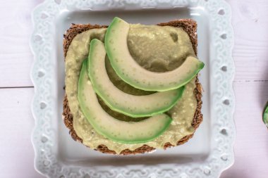 Taze Kiraz Domates ve Siyah Susam ile Organik Guacamole Avokado Spread ve Dilimler. Sağlıklı Diyet Kahvaltı Konsepti.