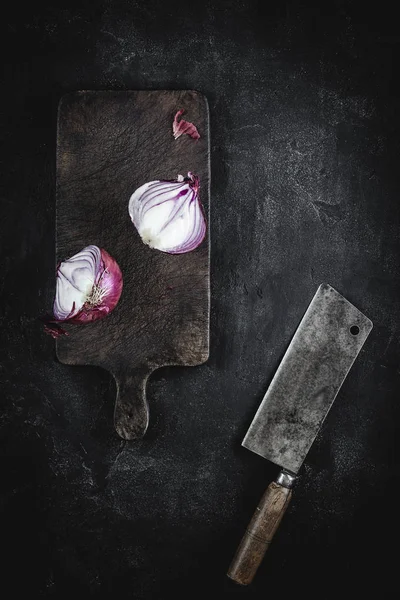 Cebolla roja a la mitad en el tablero de corte vintage con cuchilla de carne — Foto de Stock