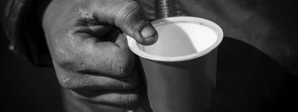 Dirty Beggar Hand Holding Plastic Cup. Povero uomo che implora per Mone — Foto Stock