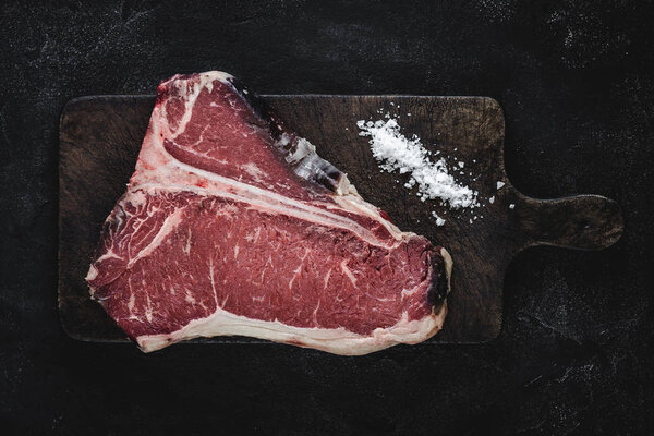 Raw T-bone Steak Dry Aged for Grill or BBQ on Vintage Cutting Board