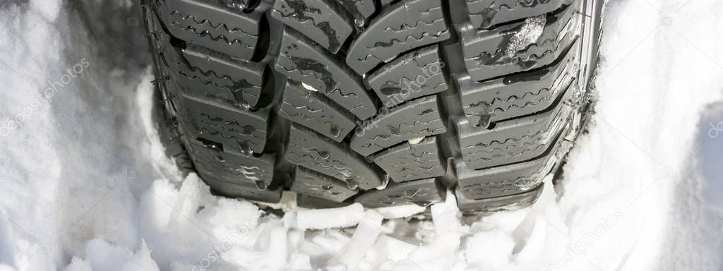 Car Tire on the Snowy Road Close Up. Winter Driving Conditions.