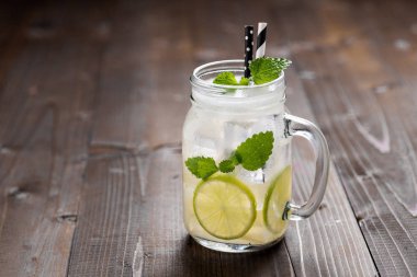 Buz ile Soğuk Limonata. Koyu Ahşap Arka Plan Üzerinde Mason Kavanoz Limon ve Nane Yaprakları.
