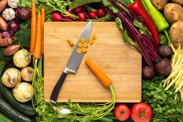 Faca de Chef na placa de corte de madeira com fundo de vegetais frescos. Conceito de alimentação saudável . — Fotografia de Stock